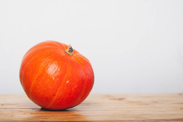 Pumpkin on a wooden table against a white wall, pumpkin minimal, - Foto, imagen