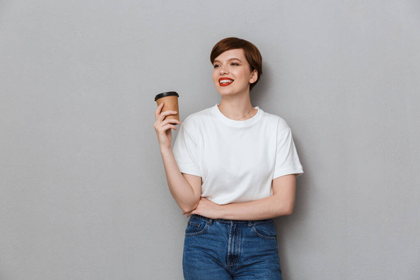 Image of joyful brunette woman wearing casual t-shirt holding ta - Fotoğraf, Görsel