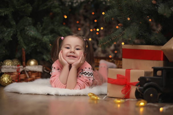 新年のクリスマスの雰囲気の中の小さな女の子。女の子は幸いです - 写真・画像