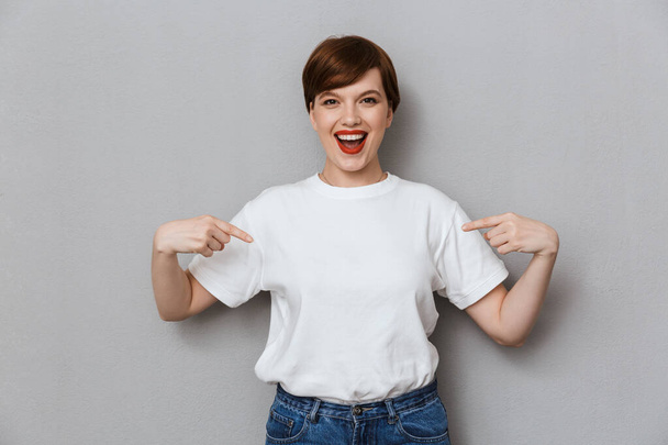Image of excited brunette woman smiling and pointing fingers at  - Foto, immagini