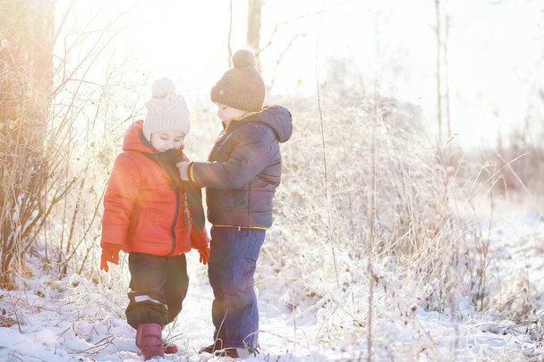 χαριτωμένα παιδιά σε ζεστά ρούχα παίζουν στο πάρκο το χειμώνα  - Φωτογραφία, εικόνα