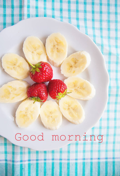 バナナとイチゴの白いプレートの碑文おはようございます - 写真・画像