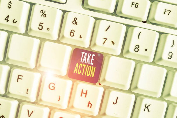Conceptual hand writing showing Take Action. Business photo text advices someone to do something or reaction right now White pc keyboard with note paper above the white background. - Photo, Image