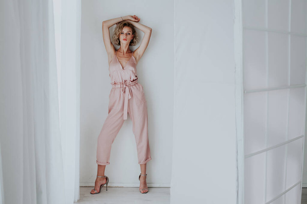 Muoti muotokuva kaunis nainen vaaleanpunainen vaatteita valkoisessa huoneessa
 - Valokuva, kuva