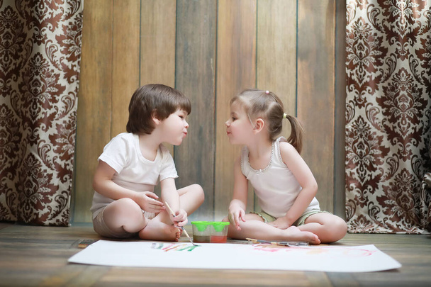 Niños pequeños pintan en una hoja grande de papel
 - Foto, imagen