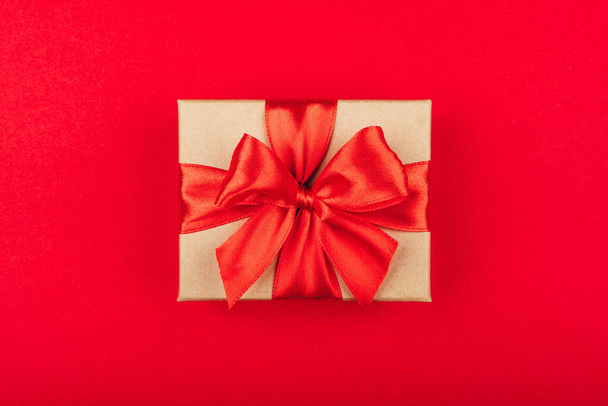 Cardboard gift box with bow on red background. - Photo, image
