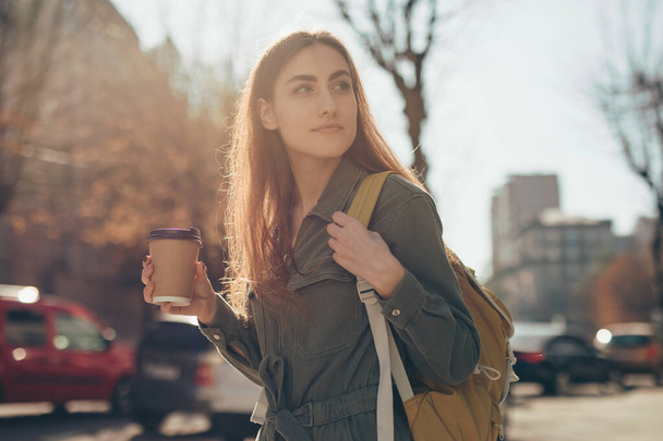 Beautiful woman holding paper coffee cup and enjoying walk in the city - Foto, Bild