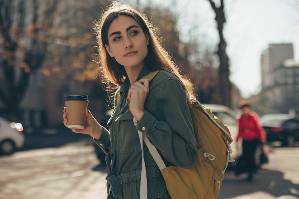 Beautiful woman holding paper coffee cup and enjoying walk in the city - Foto, immagini