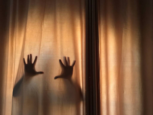 Horrorszene aus verschwommenem Schatten der Hände hinter Vorhängen, auf gespenstische Weise, Halloween-Horrornacht. mit Platz rechts für Text. Kopierraum. - Foto, Bild