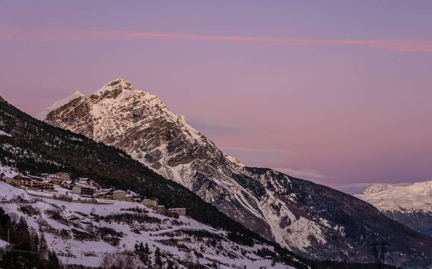 winterlandschap bij zonsondergang van de hoge Valtellina, tussen de Italiaanse centrale Alpen, dorp valdidentro, sondrio, Italië - Foto, afbeelding