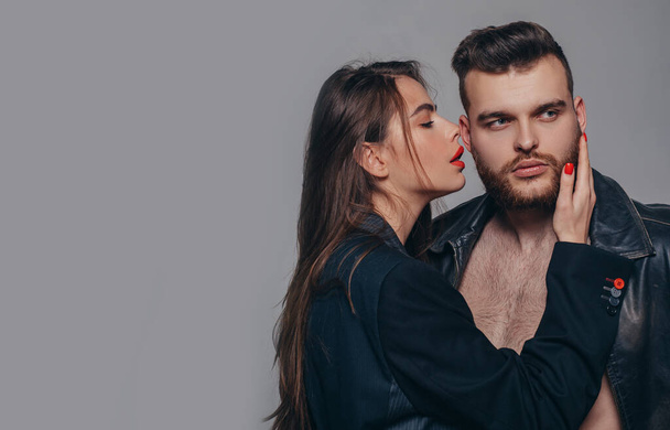 Couple passionate people in love. Passion fashion. Man brutal well groomed macho and attractive feminine girl long hair cuddling. Girlfriend passionate red lips and man leather jacket. Passionate hug - Foto, Imagem