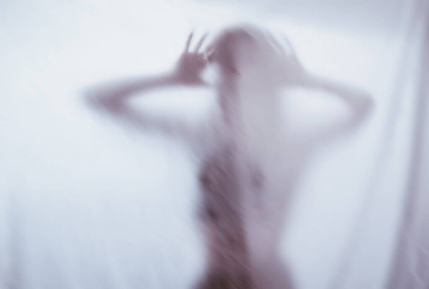 silhouette of a female sexual figure behind foggy glass. concept of the spirit of poltergeist from the other world. frightening hands of death through the fabric. - Fotoğraf, Görsel