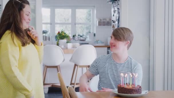 Young Downs Syndrome couple celebrating birthday blowing candles out on cake at home - shot in slow motion - Video, Çekim