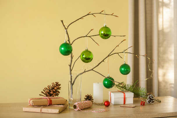 Різдвяні домашні прикраси. Зелені кульки, гілка дерева, подарункові коробки, свічки, конуси сосни, ідея для дизайну інтер'єру
. - Фото, зображення