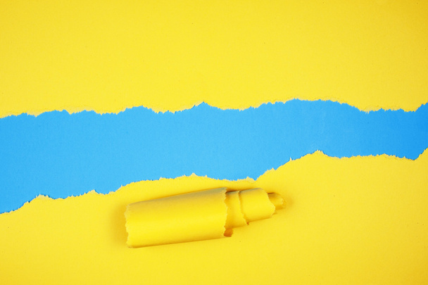 Torn yellow color paper on light blue color background - Photo, Image