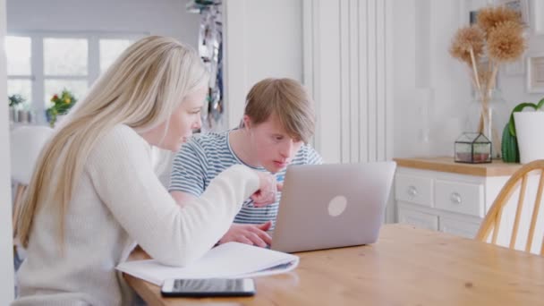 Young man with Downs Syndrome working with female home tutor on laptop at home - shot in slow motion - Filmagem, Vídeo