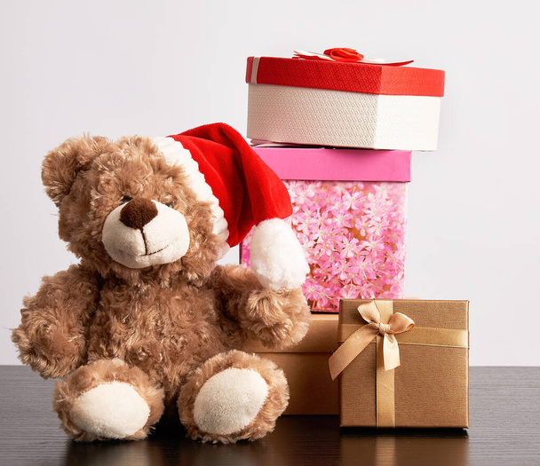 бурый плюшевый мишка и стопка различных картонных коробок в подарок
 - Фото, изображение