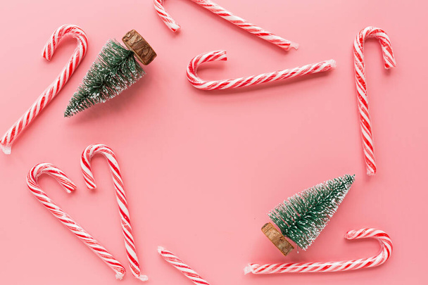 Top view of Christmas tree with many candy canes on pastel pink background. Holiday festive celebration greeting card with copy space for text. Mockup, template. Xmas concept, happy new year 2020 - Fotó, kép