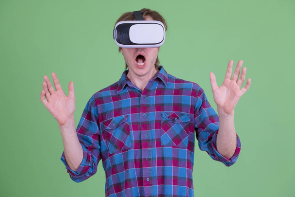 junger Hipster-Mann sieht schockiert aus, während er Virtual-Reality-Headset benutzt - Foto, Bild