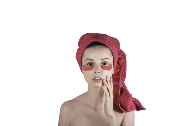 mooie jonge vrouw in een handdoek op haar hoofd en met patches op haar gezicht - Foto, afbeelding