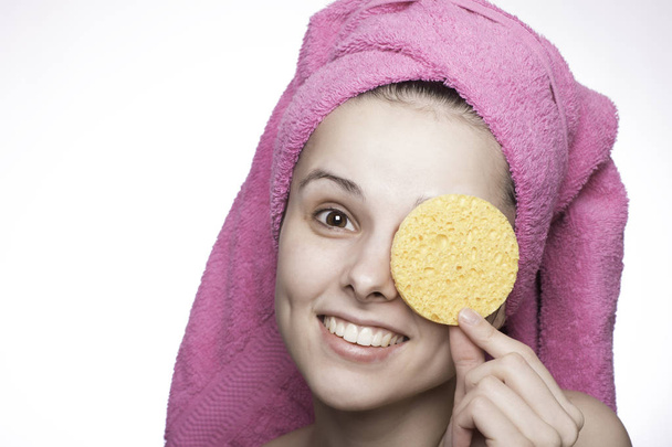 young woman in a towel on her head after shower with a sponge in hands - Foto, immagini