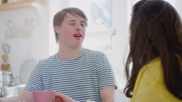 Young Downs Syndrome couple sitting around table with hot drink at home - shot in slow motion - Filmagem, Vídeo