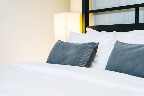schönes luxuriöses bequemes Kissen auf dem Bett mit Lampe - Foto, Bild