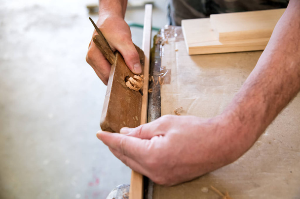 Carpenter using a planer on a plank of wood - Foto, Imagem