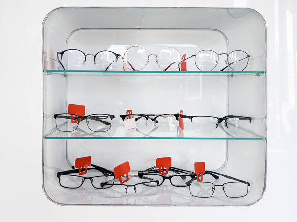 Police se skleněnými policemi s brýlemi a rámy v obchodě s optikou pro zlepšení zraku a korektní oči. Oftalmologie a zdraví. - Fotografie, Obrázek