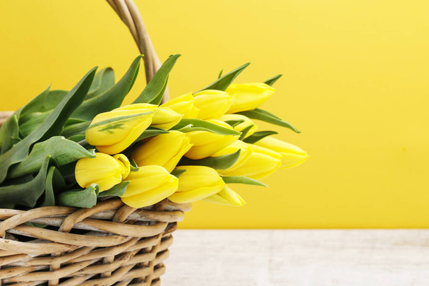 Bouquet of yellow tulips in wicker basket. - Photo, image