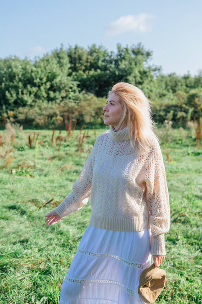 Beautiful blond woman staying and smocking cigarette in a green field - Fotó, kép