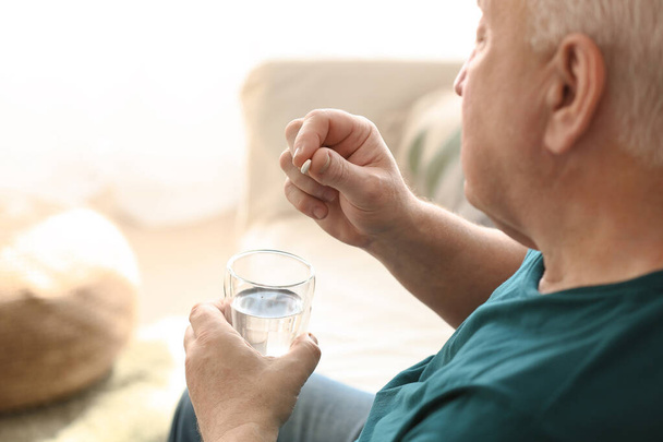 Elderly man taking medicine at home - Фото, зображення