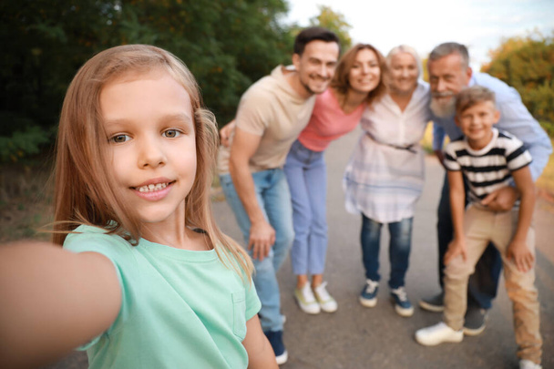 Pieni tyttö perheensä kanssa ottaa valokuvan ulkona
 - Valokuva, kuva