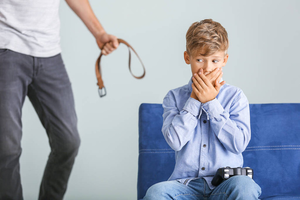 Man threatening his little son who is playing videogame at home. Physical punishment concept - Photo, Image