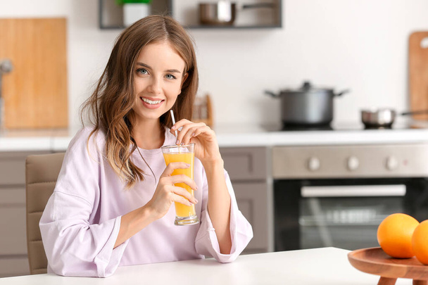 Mulher bonita bebendo suco de laranja na cozinha
 - Foto, Imagem
