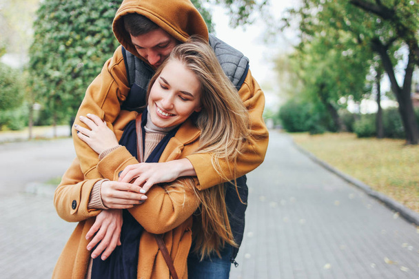 Feliz joven pareja enamorada adolescentes amigos vestidos con estilo casual sentados juntos en la calle de la ciudad de otoño
 - Foto, Imagen