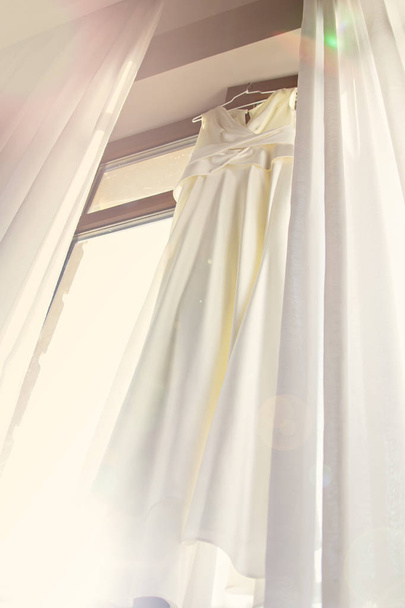 Hochzeitskleid hängt am Fenster. - Foto, Bild