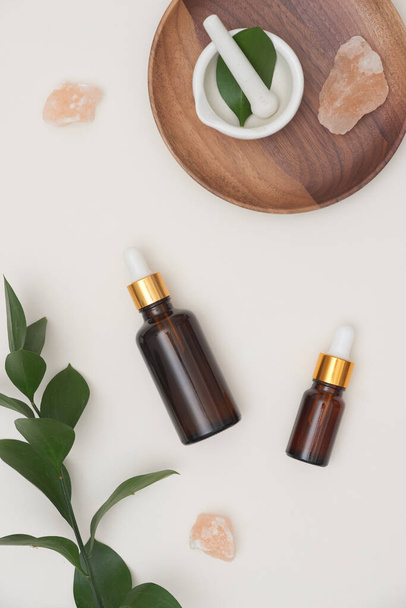 Top view. Essential oil in brown bottles with herbal, message salt on white background. Spa/ beauty product concept. - Photo, Image