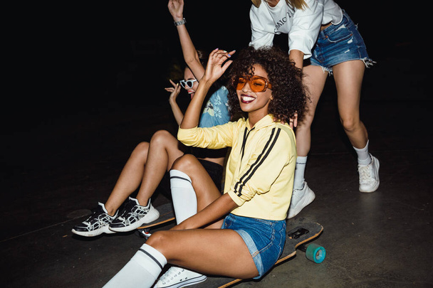Image of teenage multinational girls riding on skateboards at ni - Fotografie, Obrázek
