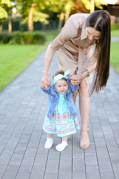Parkta küçük kızı ile yürüyen genç kadın. - Fotoğraf, Görsel