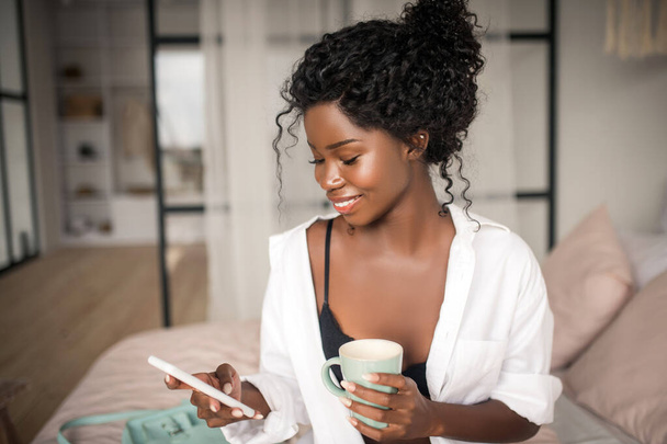 Appealing woman smiling while reading message from boyfriend - Foto, immagini