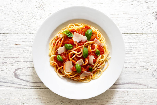 Spaghetti with tomato sauce, fresh basil and cheese. On white wo - Photo, image