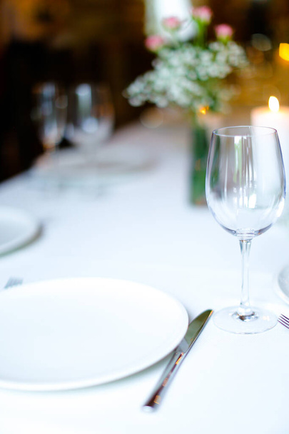 Blumenstrauß, Weinglas und Kerzen auf weißem Tisch. - Foto, Bild