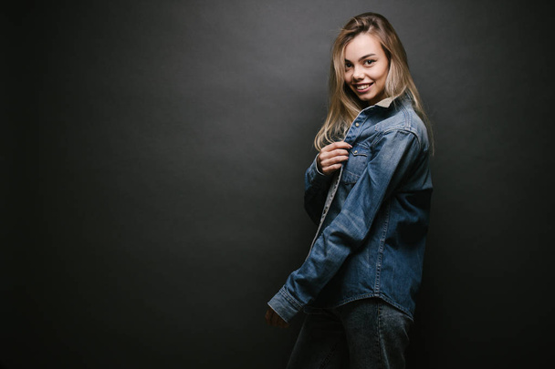 Fashion portrait of a sexy blonde woman with a make up wearing jeans clothes over gray background - Fotó, kép