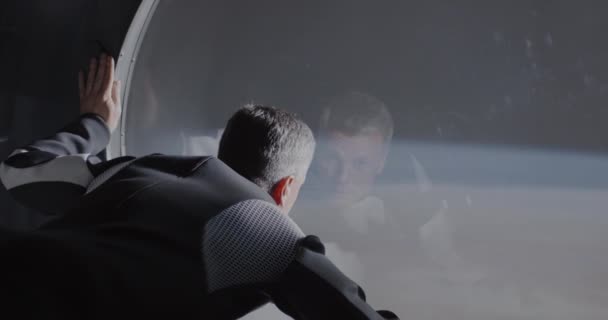 Astronauta wyglądający przez okno statku kosmicznego - Materiał filmowy, wideo