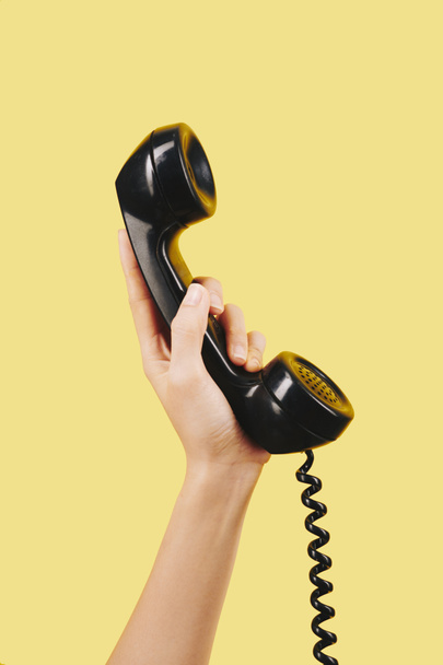 Fekete telefonkagylót tartó személy keze - Fotó, kép