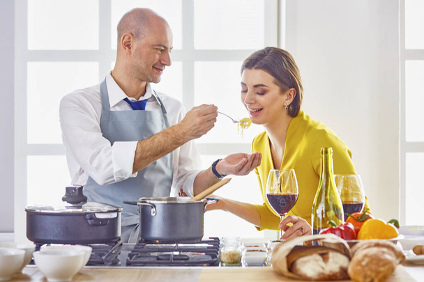 Χαμογελώντας νεαρό ζευγάρι μαγείρεμα τροφίμων στην κουζίνα - Φωτογραφία, εικόνα
