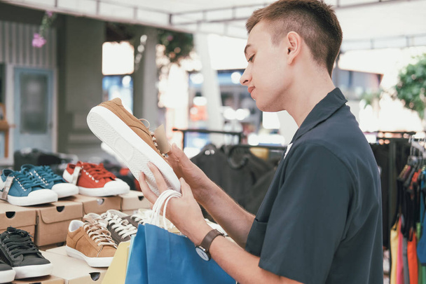 hombre sosteniendo bolsas de compras elegir zapatos en tienda
  - Foto, Imagen