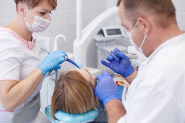Lääkäri hammaslääkäri kohtelee hampaita kaunis nuori tyttö potilas. Tyttö hammaslääkärin vastaanotossa. Lääkäri hammaslääkäri kohtelee hammas - Valokuva, kuva