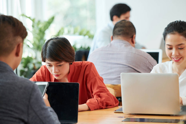 Duża grupa biznesmenów siedzi przy stole pracując online na laptopach w biurze - Zdjęcie, obraz